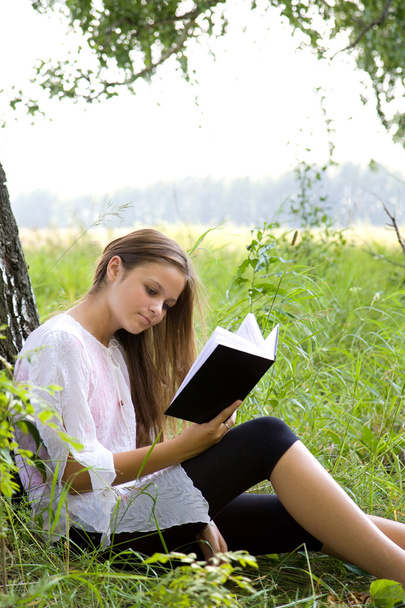 Young girl reading book in park - Valokuva, kuva