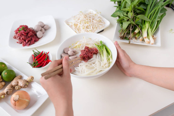 Chef cuisinière préparer soupe vietnamienne traditionnelle Pho bo avec des herbes, de la viande, des nouilles de riz
 - Photo, image