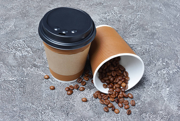 Tira papel em branco xícara de café marrom com tampa preta, suporte de copo de artesanato e feijão no fundo de concreto cinza
 - Foto, Imagem