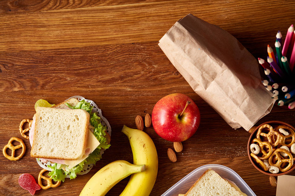 Concept of school lunch break with healthy lunch box and school supplies on wooden desk, selective focus. - Φωτογραφία, εικόνα