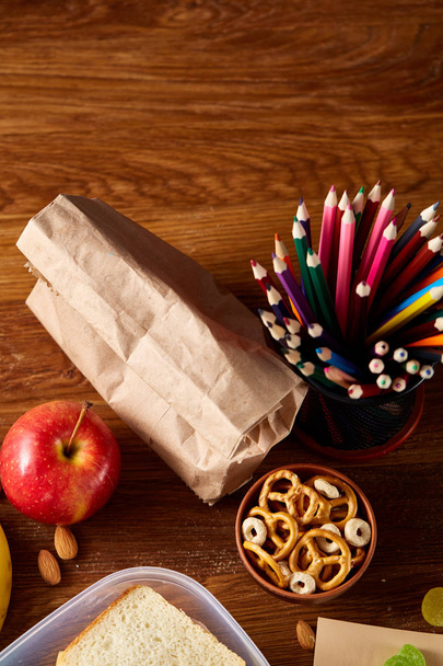 Concept of school lunch break with healthy lunch box and school supplies on wooden desk, selective focus. - Foto, Imagem