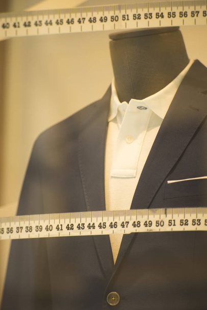 Ειδικά σχεδιασμένη βιτρίνα γίνονται για να μετρήσετε μανεκέν κατάστημα προσαρμοσμένο κοστούμι με επίσημο πουκάμισο και γραβάτα με μεζούρα. - Φωτογραφία, εικόνα