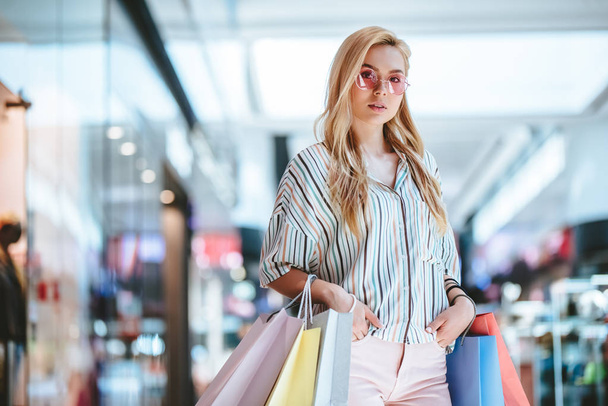 Attractive young happy woman is doing shopping with shopping bags in modern mall. - Foto, Bild