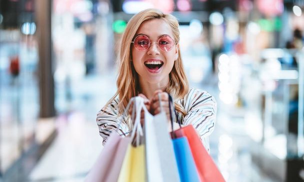 Attractive young happy woman is doing shopping with shopping bags in modern mall. - Φωτογραφία, εικόνα