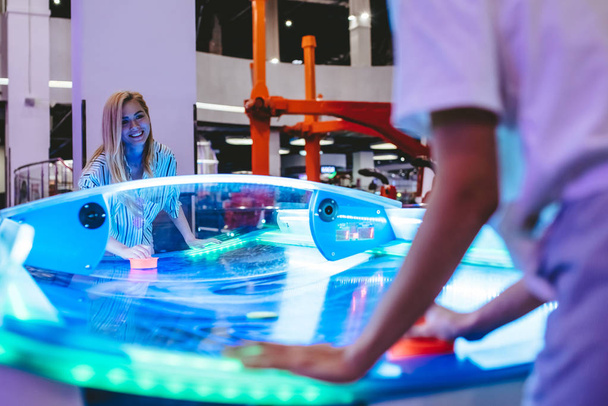 Attractive young women are having fun in amusement park. Playing table hockey together. - 写真・画像