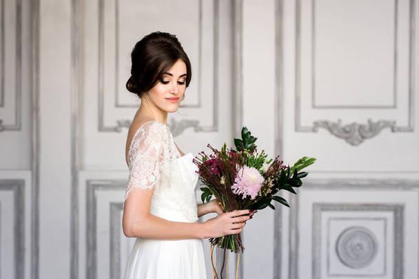 Svatební móda nevěsta s kyticí v ruce. Portrét krása nevěsty v bílých šatech. - Fotografie, Obrázek