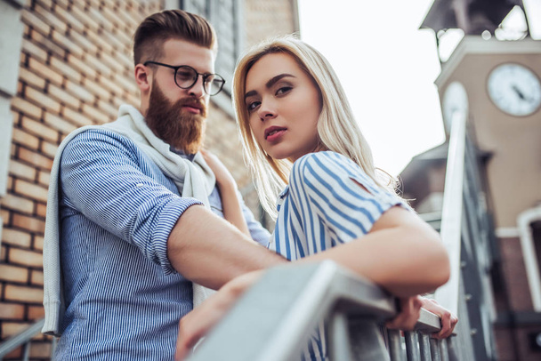 Young stylish happy couple is spending time together outdoors. Attractive woman and handsome bearded man are having fun together in the city. - Foto, Bild