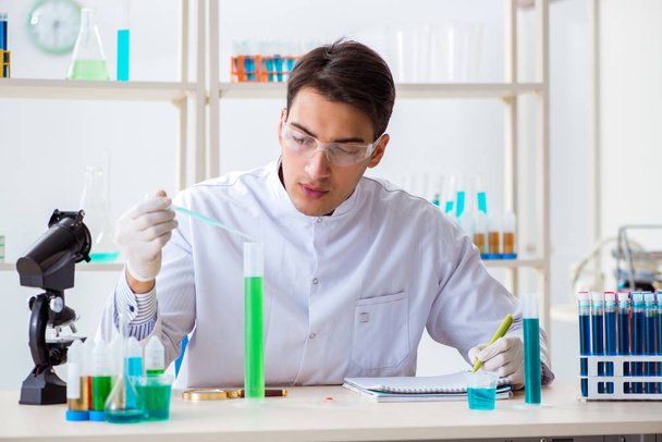 Nuori kemisti opiskelija työskentelee laboratoriossa kemikaalien - Valokuva, kuva
