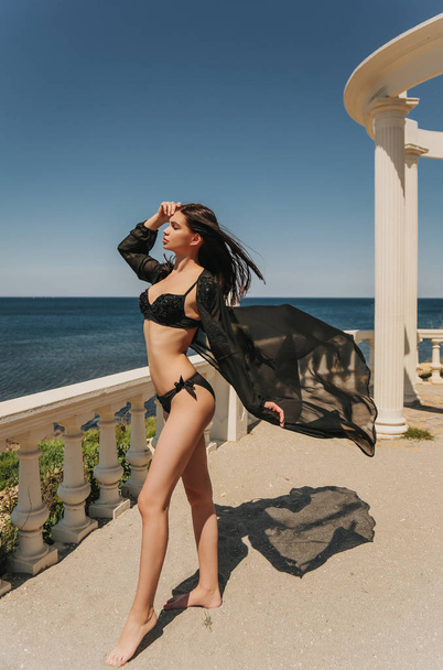 fashion outdoor photo of beautiful sexy woman with dark hair in luxurious bikini relaxing on the beach - 写真・画像