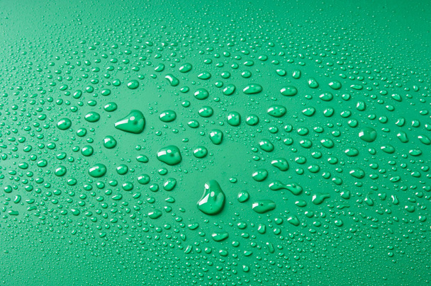 Vízcseppek, különböző méretű, egy zöld háttér - Fotó, kép