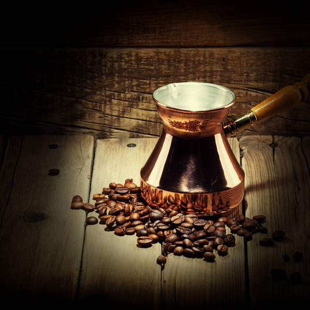 grains de café dispersés et turque de café de cuivre sur fond en bois
 - Photo, image