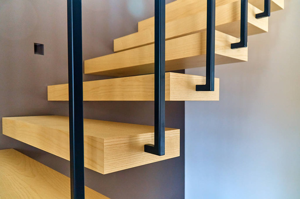 Escaliers flottants. Escaliers en bois de frêne avec rampe attachée au mur brun et menant au deuxième étage à l'intérieur élégante maison moderne
 - Photo, image