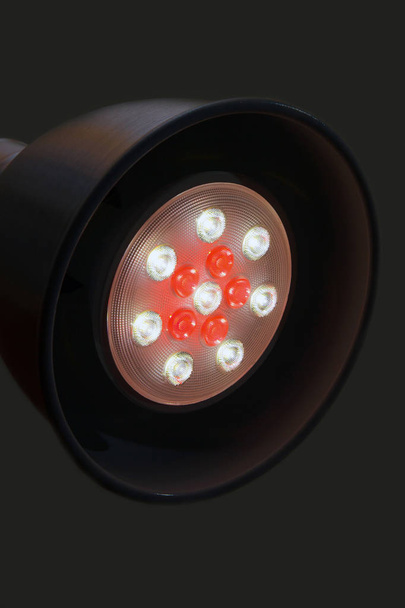 Primo piano di una lampada LED di colore bianco e rosso. Lampada da tavolo rotonda con una nuova lampada tecnologica su sfondo nero
. - Foto, immagini