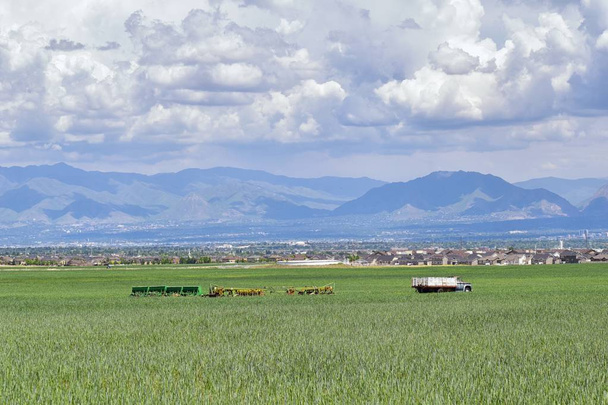 Vintage Farm Truck and harvest machinery with Panoramic view of Wasatch Front Rocky Mountains, Great Salt Lake Valley in early spring with melting snow and Cloudscape. Utah. USA. - Photo, Image