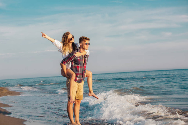 Young woman piggybacking on young boyfriend on beach - Photo, image