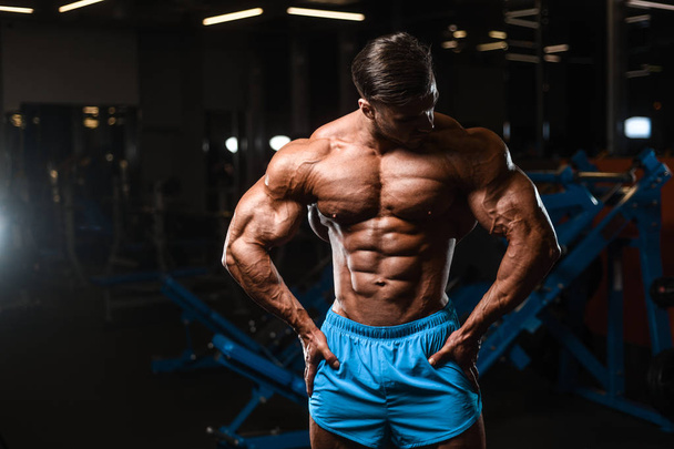 Handsome young fit muscular caucasian man of model appearance workout training in the gym gaining weight pumping up muscle, poses, drinks water  fitness and bodybuilding sport nutrition concept - Foto, afbeelding