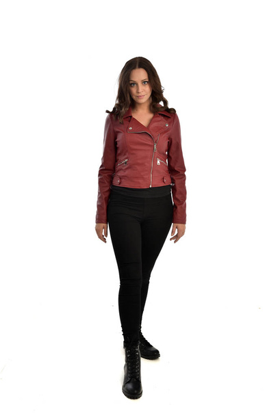 Pełna długość Portret brunetka Girl ubrany czerwona skórzana kurtka, czarne dżinsy i buty. Stojący poza, na białym tle na tle białego studia. - Zdjęcie, obraz