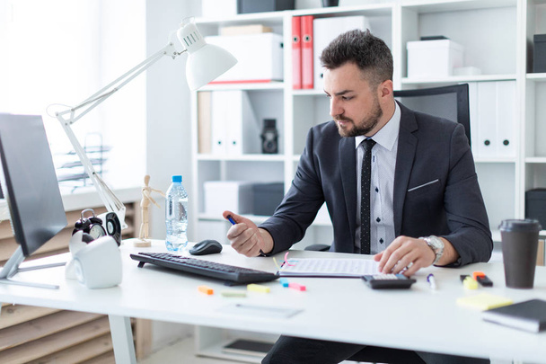 Egy férfi ül az irodában, az asztalnál, és rákattint egy toll. - Fotó, kép