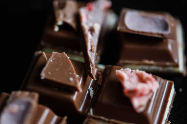 Close-up macro photo of chocolate pieces, simple composition on a black background - Fotó, kép