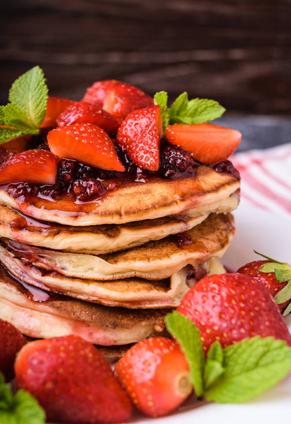 Delicious american pancakes with fresh strawberries, jam and mint leaves. Served  on a white plate. Healthy breakfast. - Foto, Bild