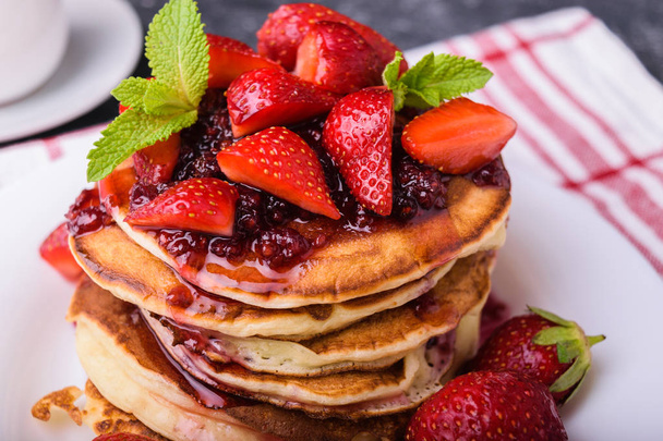 Delicious american pancakes with fresh strawberries, jam and mint leaves. Served  on a white plate. Healthy breakfast. - 写真・画像