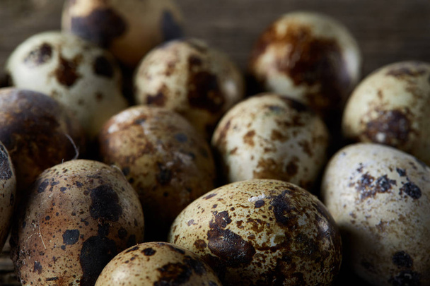 Spotted quail eggs arranged on the background of old wooden boards, with copy-space, selective focus. - Zdjęcie, obraz
