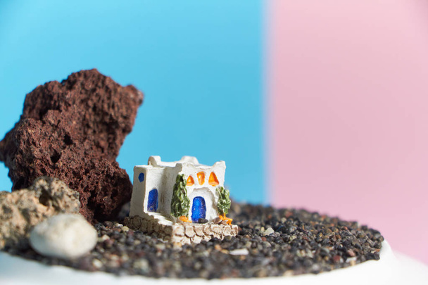 Modelo animado de una casa griega sobre una roca sobre un fondo neón y rosa
. - Foto, imagen