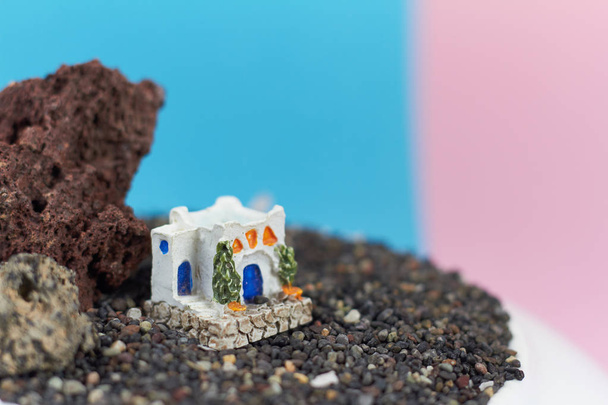 Modelo animado de una casa griega sobre una roca sobre un fondo neón y rosa
. - Foto, imagen