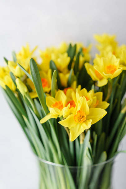 Narcissus of yellow color in glass vase. Floral natural backdrop. Shallow focus. Vertical photo, Wallpaper - Fotó, kép