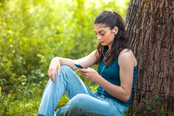 Beautiful girl resting in forest speak by cell phone, sports girl. - Foto, Imagem