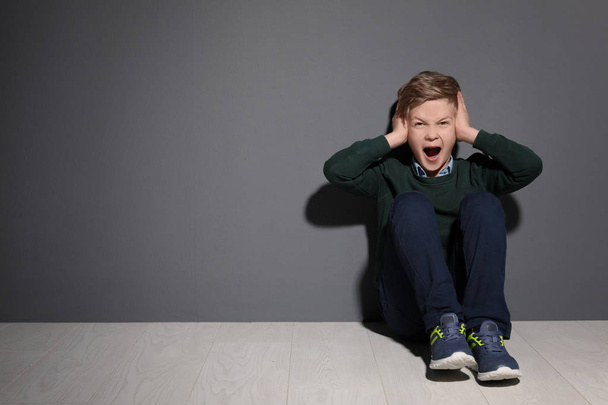 Depressed little boy sitting on floor indoors. Time to visit child psychologist - Foto, afbeelding