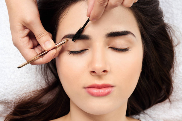 Young woman having professional eyebrow correction procedure in beauty salon, closeup - Photo, Image