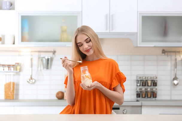 Young woman with yogurt in kitchen - 写真・画像