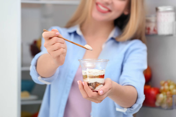Young woman with yogurt in kitchen, closeup - Foto, afbeelding