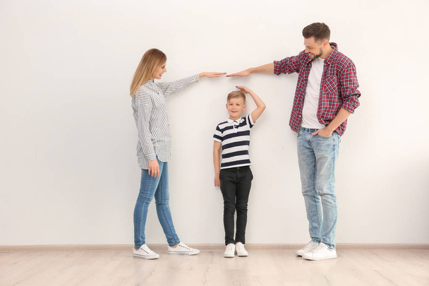 Parents measuring their son's height indoors - Foto, afbeelding