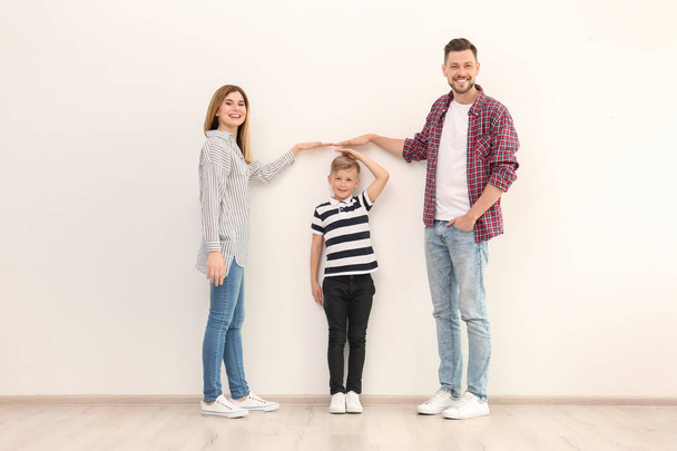 Parents measuring their son's height indoors - Valokuva, kuva