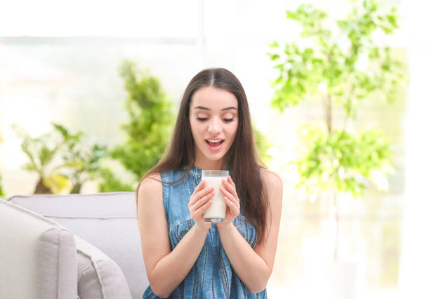 Beautiful young woman drinking milk at home - Zdjęcie, obraz