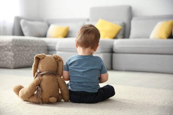 Little boy with toy sitting on floor in living room. Autism concept - Foto, Imagen