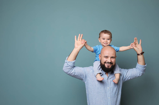 Portrait of dad and his little son on color background - Foto, Imagen