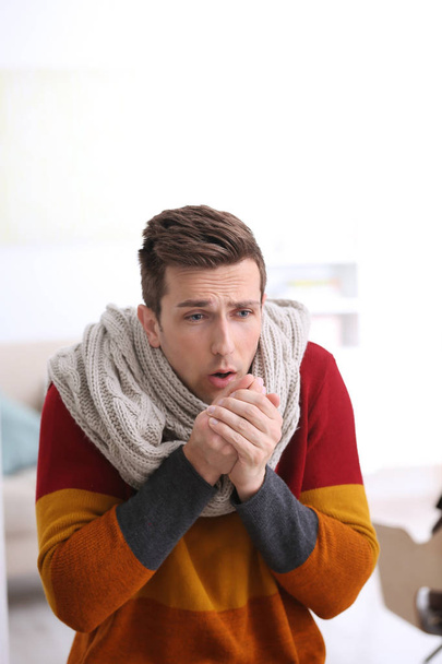 Sad young man suffering from cold on blurred background - Photo, image