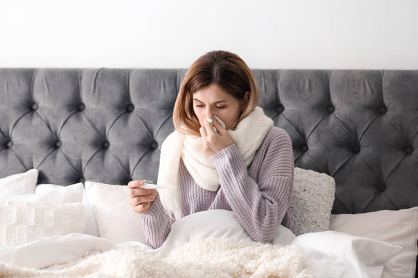 Femme malade avec tissu et thermomètre souffrant de froid au lit
 - Photo, image