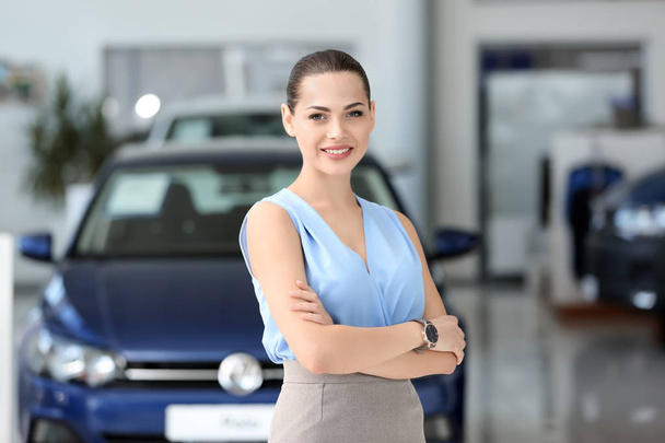 Attractive young saleswoman in car dealership - Фото, изображение