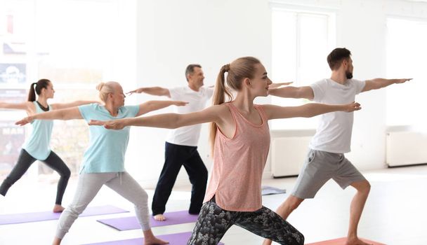 Group of people in sportswear practicing yoga indoors - Foto, Imagen