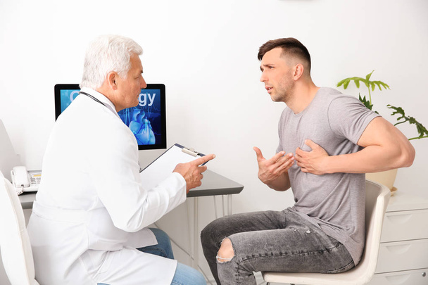Male doctor working with patient in clinic. Cardiology consultation - Foto, Bild