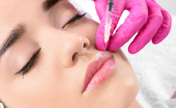 Young woman getting lip injection in beautician salon, closeup - Foto, immagini