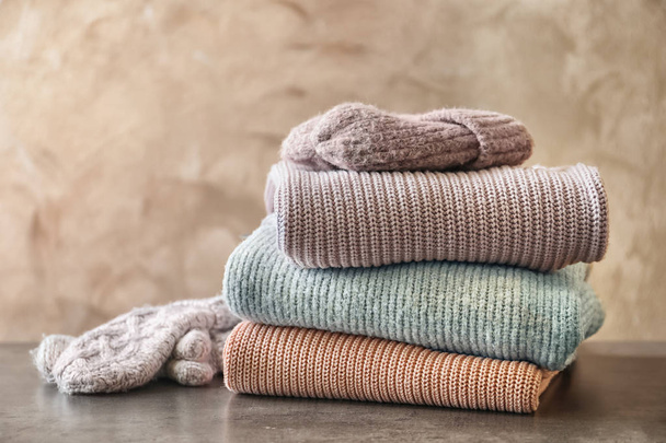 Stack of warm knitted clothes on table - Foto, Bild