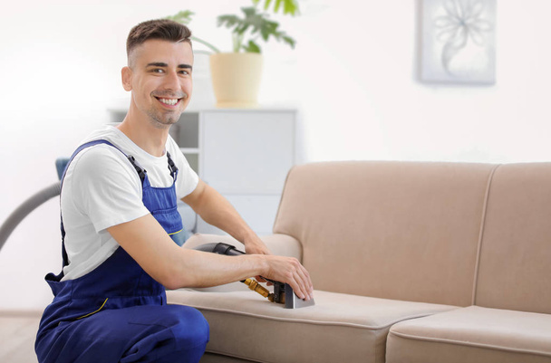 Dry cleaning worker removing dirt from sofa indoors - Foto, immagini