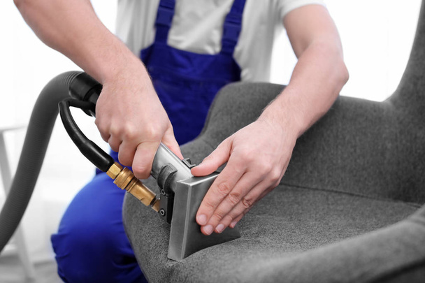 Dry cleaning worker removing dirt from armchair indoors - Foto, Imagem