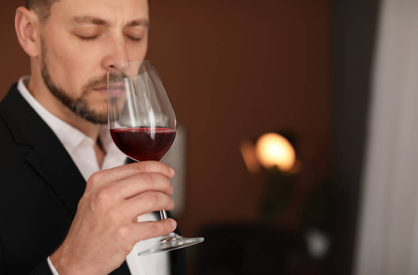 Young man with glass of wine indoors - Foto, Bild