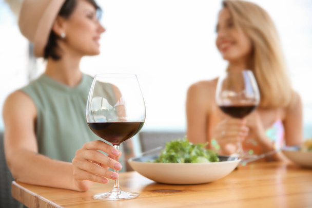 Young women with glasses of wine at table - Foto, Imagen